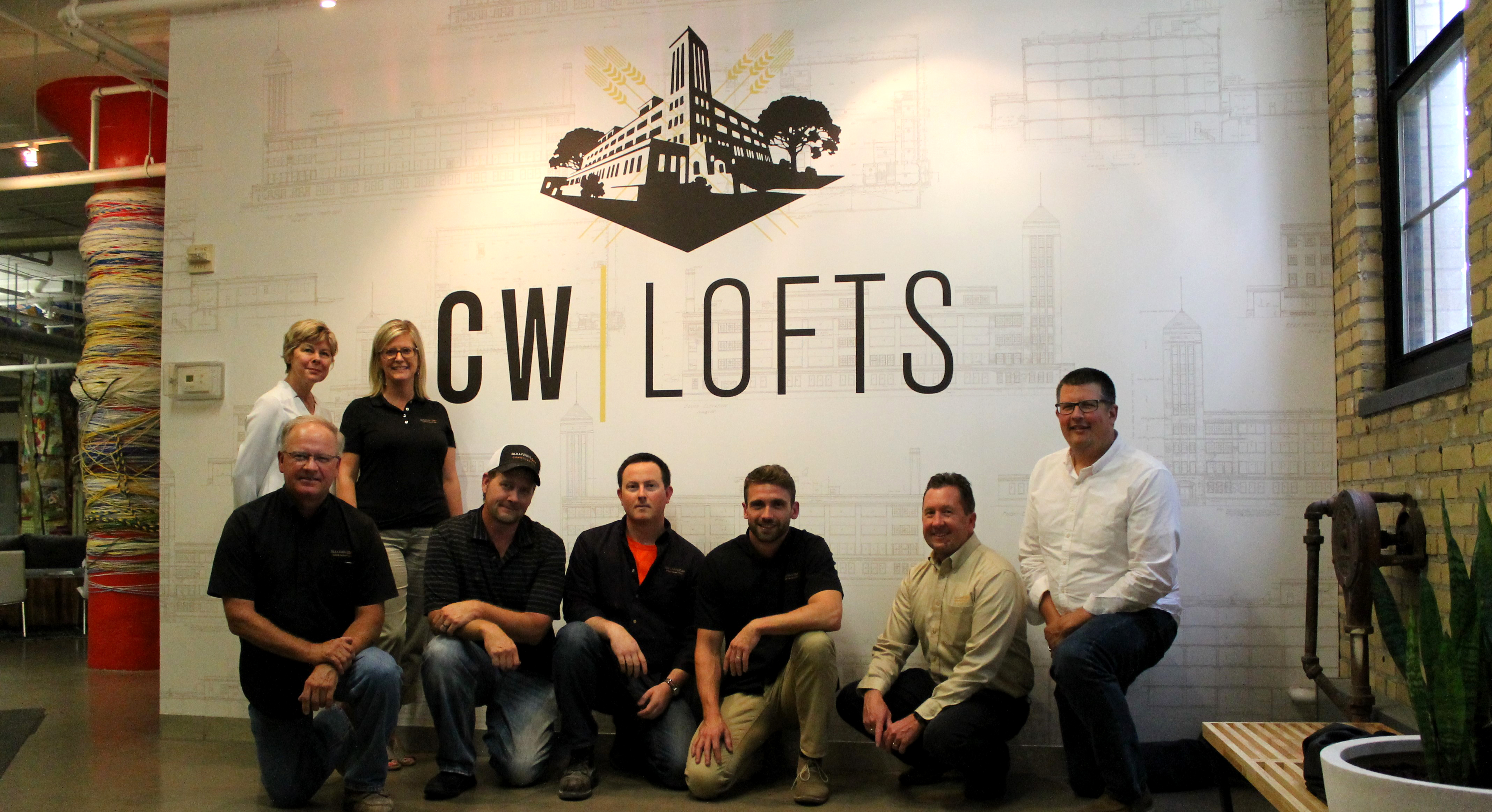 Team standing in front of CW Lofts signage.